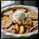 Delicious classic Southern peach cobbler served warm with vanilla ice cream.