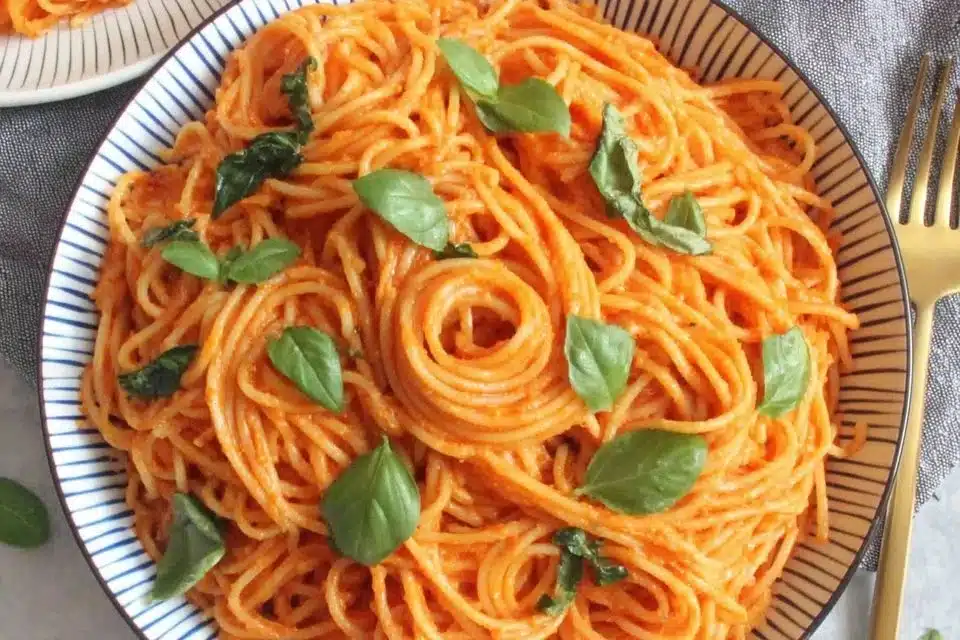 Creamy roasted red pepper pasta dish garnished with herbs