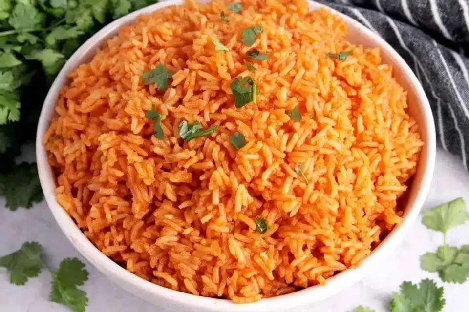 Bowl of flavorful restaurant-style Mexican rice garnished with herbs