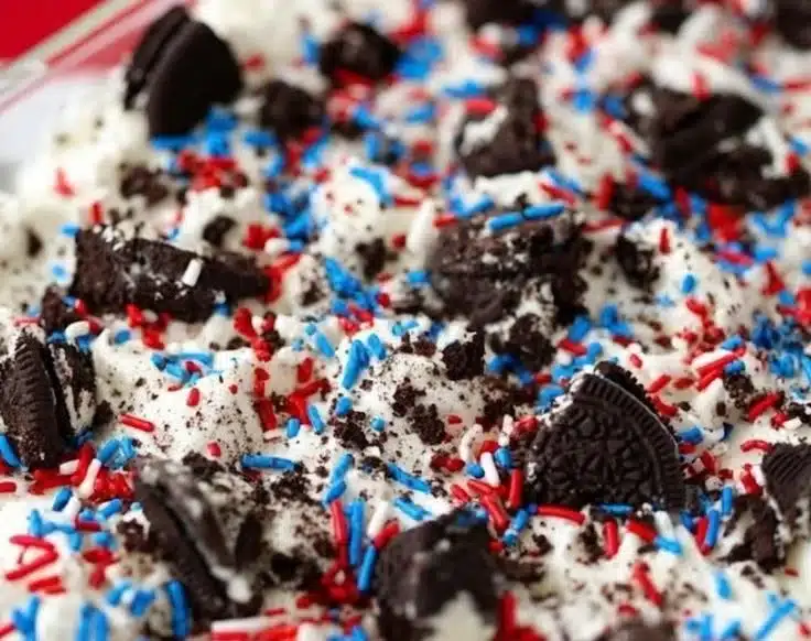 No-bake Oreo cheesecake bars topped with crushed Oreos and chocolate drizzle
