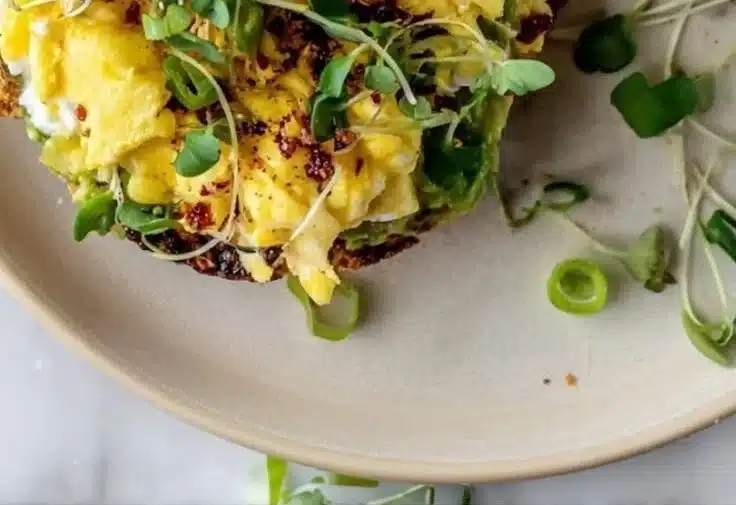 Crispy hashbrown avocado toast served on a plate with garnish