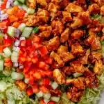 Honey-glazed spicy chicken salad bowl with fresh vegetables and dressing